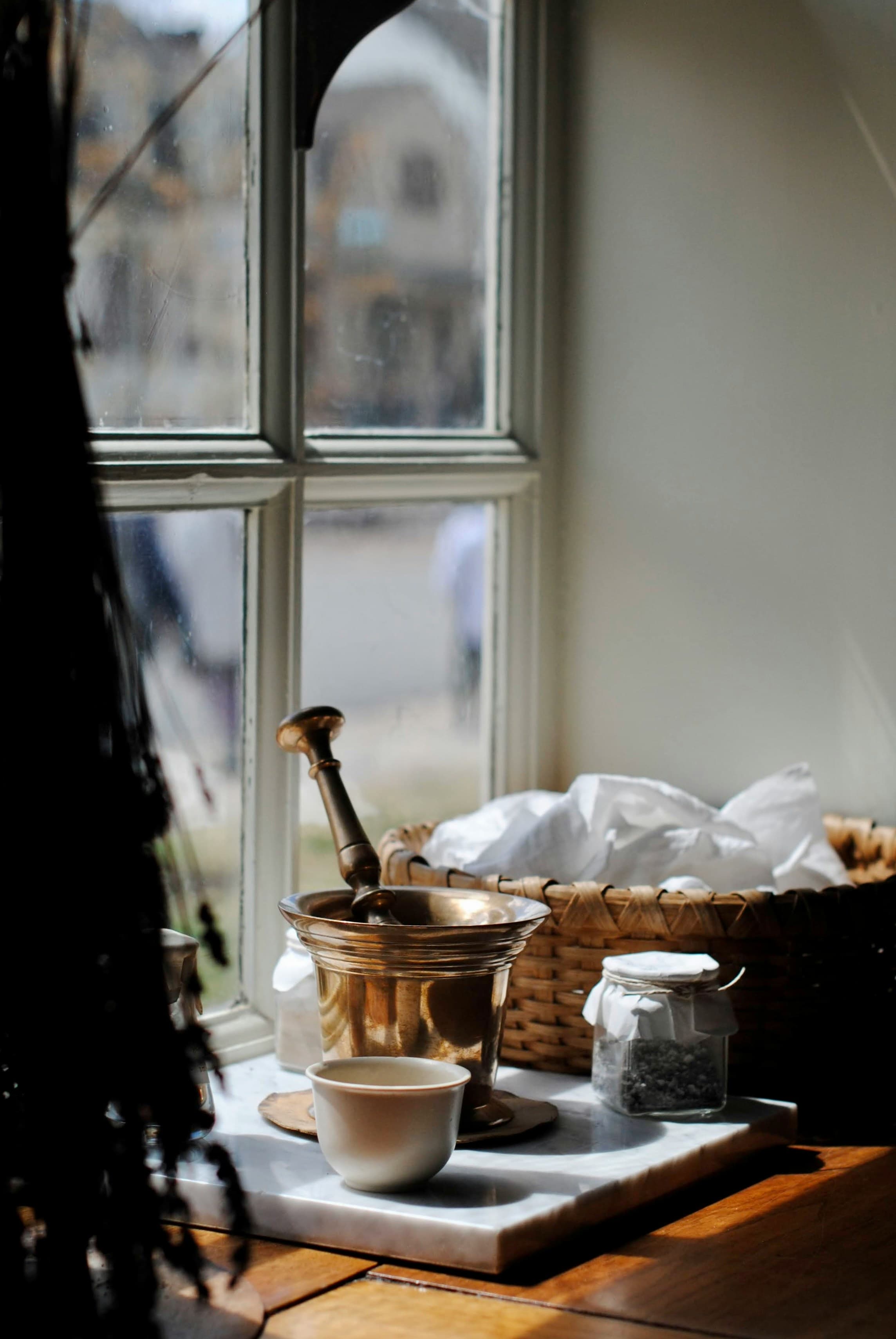 A brass mortar and pestle on a marble slab by a cottage window