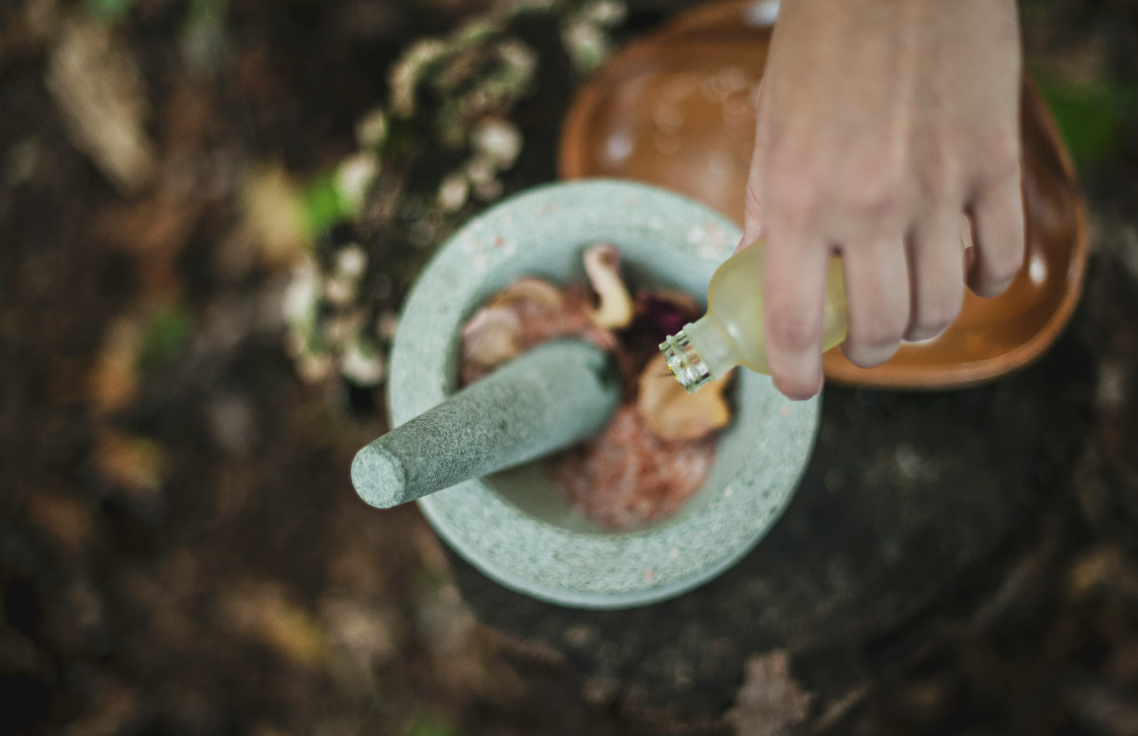 Hands grinding herbs and salt in a stone mortar and pestle